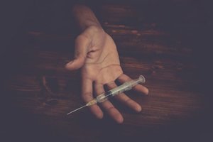 individual holding a needle shows signs of a heroin overdose