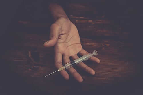 individual holding a needle shows signs of a heroin overdose